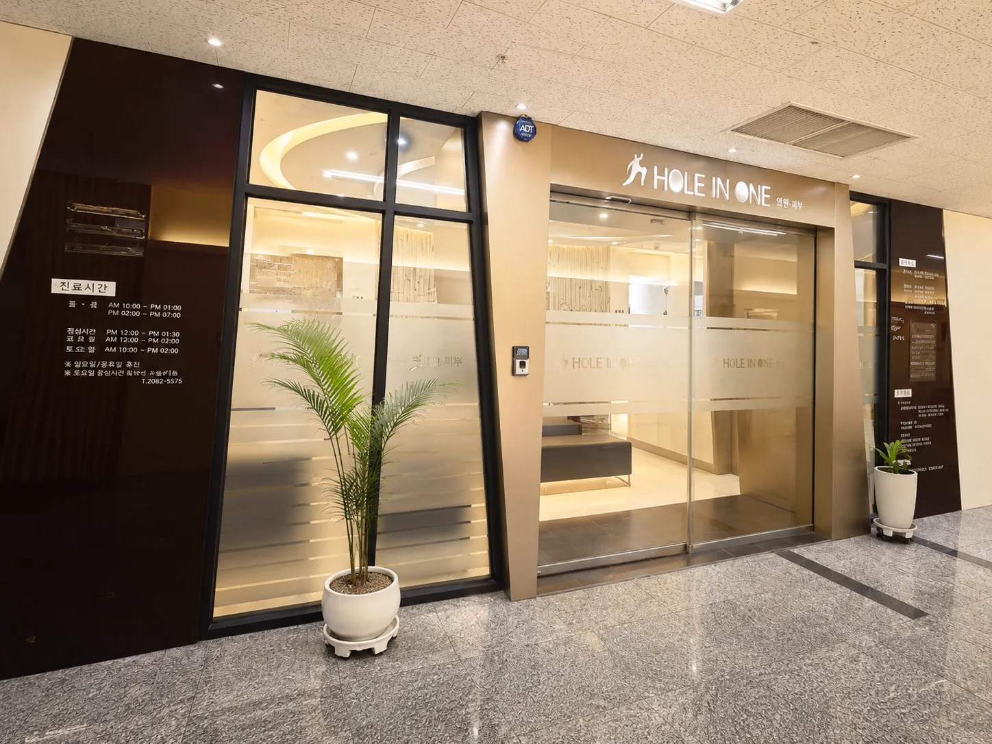 건물 복도에서 본 홀인원의원 출입구와 진료시간 안내